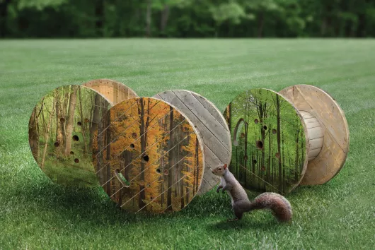 Trois bobines en bois dans un champ gazonné.