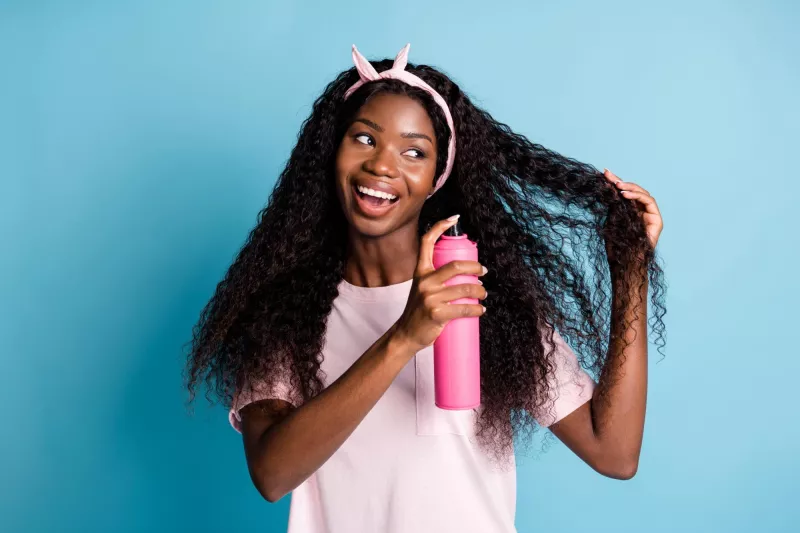 Photo d’une femme utilisant un produit aérosol dans ses cheveux longs